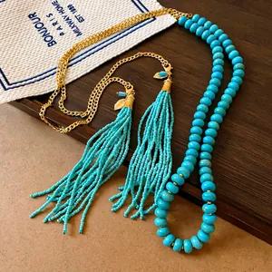 Gros plan d'un collier de perles turquoise bohème avec longue frange et chaîne dorée
