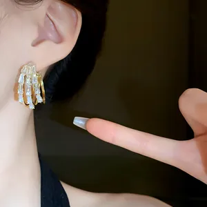 Detailansicht eleganter dreilagiger Goldohrringe mit Baguette-Kristallen am Ohr.