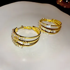 Detailansicht von dreilagigen Gold-Creolen mit eleganten Kristallen im Baguetteschliff.
