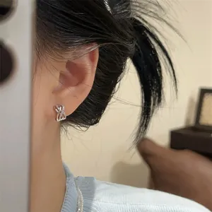 Close-up of elegant silver crossover hoop earring with pavé zircon stones on ear