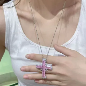Detail shot of a large pink zircon cross pendant necklace worn on a white tank top