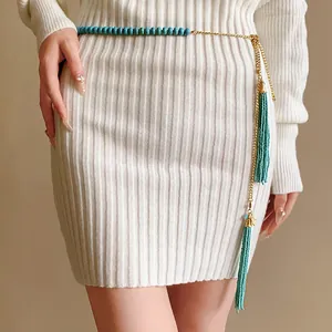 Chaîne de taille bohème en perles turquoise avec de longs glands dorés sur robe blanche