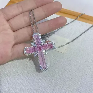 Detailed view of cross pendant necklace with large pink baguette stones and zircon border
