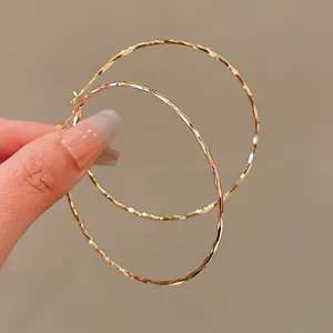 Detail view of gold hoop earrings featuring a hammered metallic textured surface.