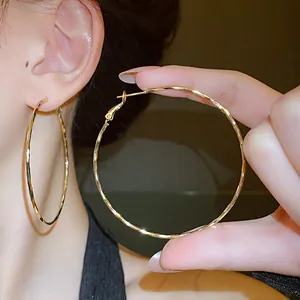 Detailed close-up view of large gold twisted hoop earrings showing hammered texture design