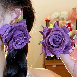 Eleganti orecchini a rosa in tessuto viola con dettagli a goccia d'acqua e ago in argento.