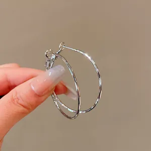 Macro detail view of silver-plated hoop earrings with a unique hammered and textured finish