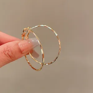 Close-up detail of textured gold hoop earrings with silver needles for a modern look
