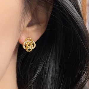 Elegant gold hollow flower stud earrings with sparkling cubic zirconia on model