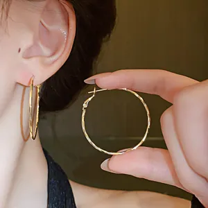 Close-up detail of gold twisted hoop earrings with an elegant glossy metal finish