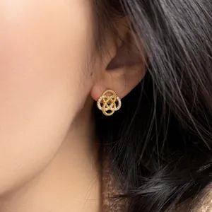 Elegant gold hollow flower stud earrings with zircon inlay worn by an Asian model