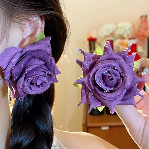 Dettaglio di eleganti orecchini a rosa in tessuto viola con perline a goccia d'acqua