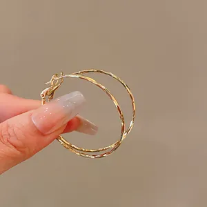 Close-up view of elegant gold twisted hoop earrings showing refined textured metal finish