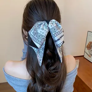 Vintage paisley print oversized bow hair clip styled on model's long wavy hair back
