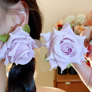 Vista dettagliata di eleganti orecchini a rosa in tessuto viola con gocce d'acqua.