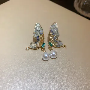 Dettaglio ravvicinato di eleganti orecchini a farfalla con cristalli e perle bianche.