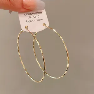 Detailed view of large gold-tone hammered texture hoop earrings with premium silver needles.