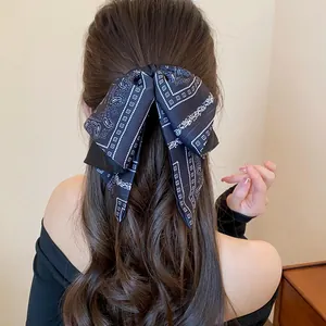 Detailed back view of a large vintage black paisley bow hair clip on long wavy hair.