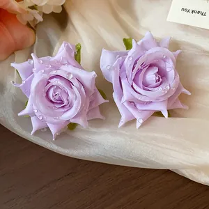 Primo piano di orecchini a rosa in tessuto viola con delicati dettagli di rugiada