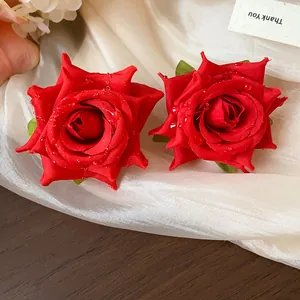 Macro di orecchini a forma di rosa in tessuto rosso con gocce di rugiada