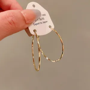 Macro detail of textured gold hoop earrings with hammered metal finish and curved design.