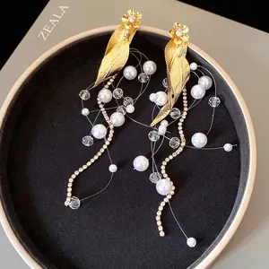Boucles d'oreilles vintage avec feuilles d'or, perles et glands en cristal dans un écrin