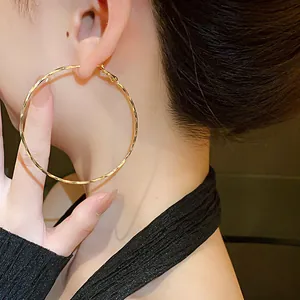 Close-up detail showing the twisted metal texture of a large golden hoop earring