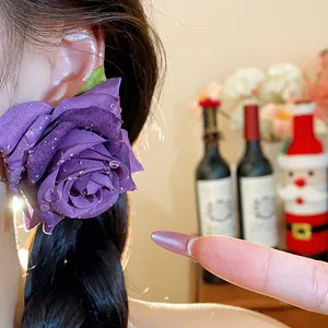 Primo piano di un orecchino a rosa in tessuto viola con delicati accenti di rugiada