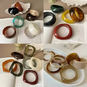 Retro hars armbanden met marmerpatroon op vintage boeken in diverse kleuren.