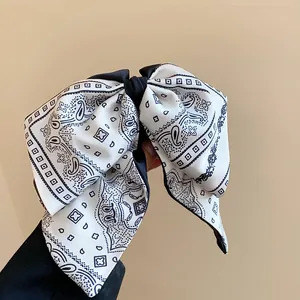 Close-up of retro paisley pattern bow hair clip with elegant black and white design