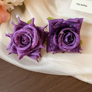 Vista dettagliata di orecchini a rosa in tessuto viola con gocce d'acqua realistiche