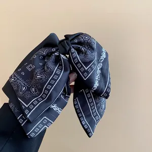 Detail view of retro black bandana paisley bow hair clip with elegant pattern