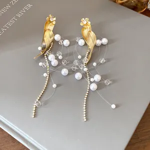Vue détaillée de boucles d'oreilles à pampilles feuille d'or et perles avec strass