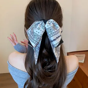 Detailed view of a stylish retro paisley print bow hair clip on an elegant half-up hairstyle