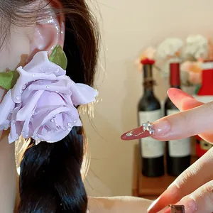Primo piano di un orecchino a fiore in tessuto viola con perline effetto rugiada