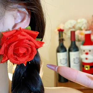 Primo piano di grandi orecchini a rosa in tessuto rosso, stile dolce ed elegante.