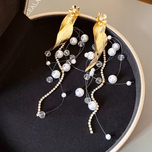 Gros plan de boucles d'oreilles rétro françaises avec feuilles dorées et perles blanches