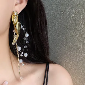Gros plan de boucles d'oreilles élégantes à pampilles en feuille d'or et perles