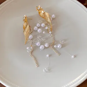 Vue détaillée d'élégantes boucles d'oreilles feuille d'or avec glands en perles et cristal