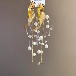 Vue détaillée d'élégantes boucles d'oreilles feuilles d'or et fleurs à pompons