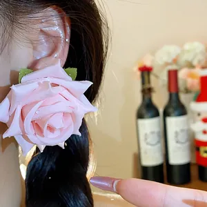 Dettaglio ravvicinato di un grande orecchino a rosa in tessuto rosa indossato con eleganza
