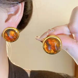 Primo piano di orecchini retrò in ambra con montatura dorata sulla modella