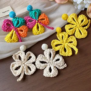 Macro view of colorful woven raffia clover earrings with silver needles for summer
