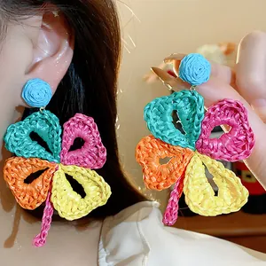 Detailed macro shot of colorful raffia woven flower earrings with intricate braided texture.