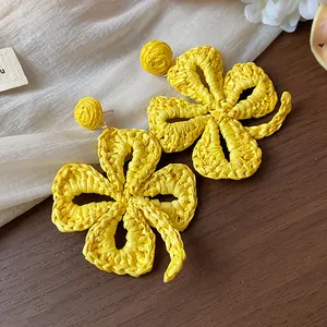 Detailed view showing the intricate yellow raffia woven texture of handmade flower earrings