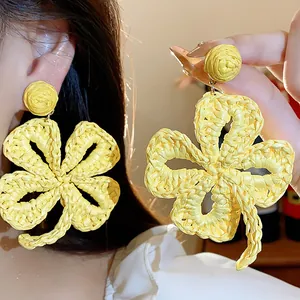 Detail shot of handmade yellow raffia woven flower earrings with vacation style