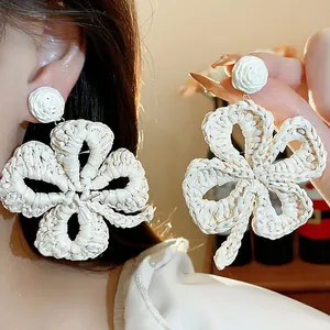 Detailed macro view of handmade cream raffia woven flower earrings for a boho summer look