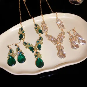 Detailed view of teardrop rhinestone necklace and matching earrings in green and clear colors