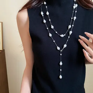 Close-up detail of a French style layered necklace with irregular pearls on a black top