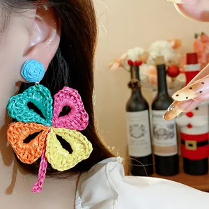 Close-up of colorful raffia woven flower earring worn by model in holiday style